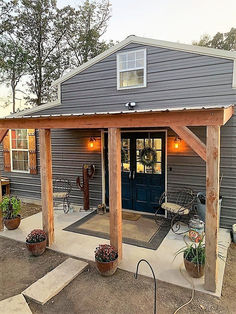 a house with a blue door and some plants on the front porch, surrounded by potted plants