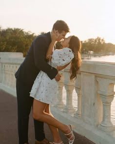 a man kissing a woman on the cheek while standing next to a railing with water in the background