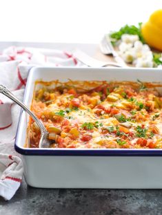 a casserole dish with tomatoes, cheese and parsley in it on a table