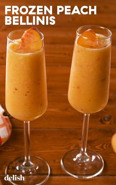 two glasses filled with frozen peach bellini on top of a wooden table