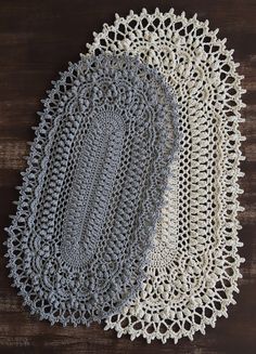 two crocheted doily on a wooden surface with one white doily and the other gray doily