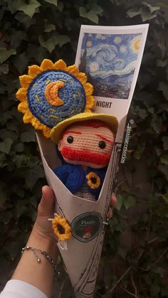 someone is holding up a crocheted sunflower with a small doll in it