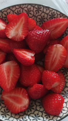 a bowl filled with sliced strawberries on top of a white and black table cloth