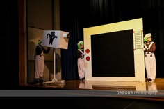 three mannequins dressed as clowns stand in front of a blackboard