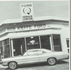 an old photo of a car parked in front of a service center