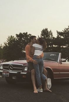 two people hugging each other in front of a car