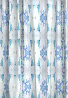 a curtain with blue flowers on it in front of a white wall and window sill