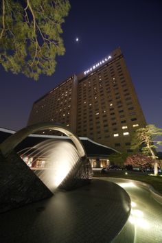 the hotel is lit up at night with lights shining on it's facade and surrounding trees