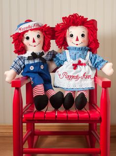 two red haired dolls sitting on a red chair