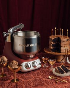 a table topped with cakes and desserts on top of a red cloth covered table