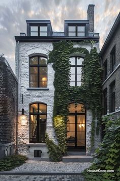 a house with ivy growing on the side of it's face and windows that are open