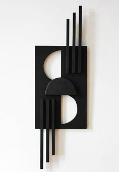 a black sculpture on a white wall in the shape of a rectangle and circles