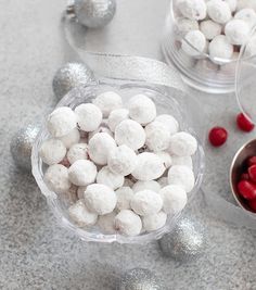 a bowl filled with white and red candies next to other silver christmas decorations on a table