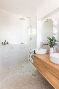 a bathroom with two sinks, a shower and a wooden counter in front of it