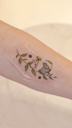 a small tattoo on the arm of a woman with flowers and a cat in it