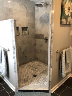 a walk in shower sitting inside of a bathroom next to two towels hanging on the wall