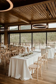 the tables are set with white linens and place settings for guests to sit at