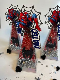 two spiderman candy stands on top of confetti sprinkles and silver stars