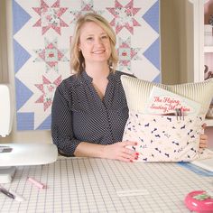 a woman sitting at a table with a pillow and sewing machine in front of her