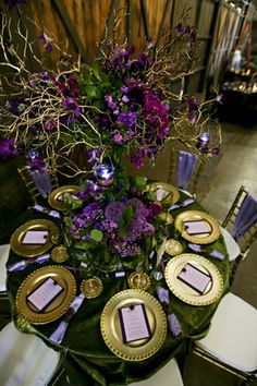 a table with purple flowers and candles on it