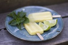 popsicles with limes and mint on a blue plate sitting on a wooden table