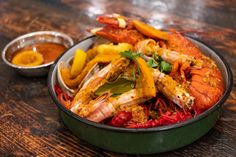 a bowl filled with shrimp and vegetables next to dipping sauce