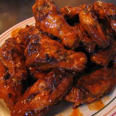 a white plate topped with chicken wings covered in bbq sauce on top of a table