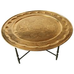 an ornately decorated gold tray sits on a metal stand with two legs and a black base