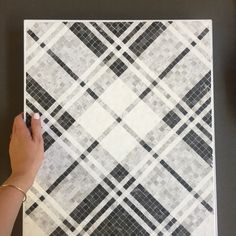 a person is painting a black and white checkered pattern on a piece of paper