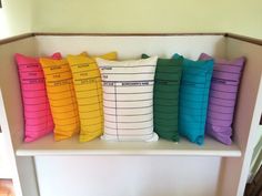 four colorful pillows sitting on top of a white shelf