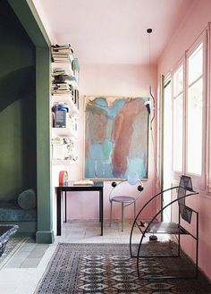 a living room with pink walls and rugs on the floor in front of a painting