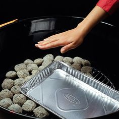 a person is reaching for some food in a pan with rocks and chopsticks