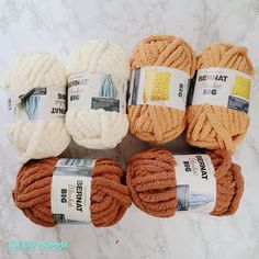 several balls of yarn sitting on top of a marble counter with white and orange colors