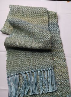 a green and blue scarf laying on top of a table