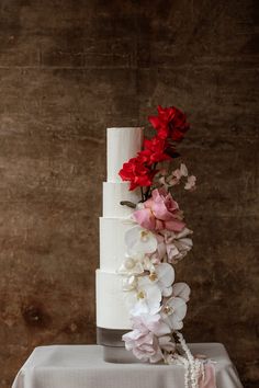 a wedding cake with flowers and pearls on the top is sitting on a tablecloth