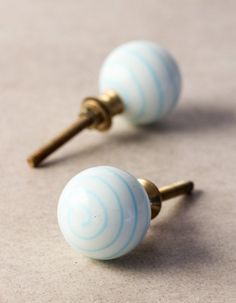 two blue and white striped glass knobs on gold toned brass posts with screw backs