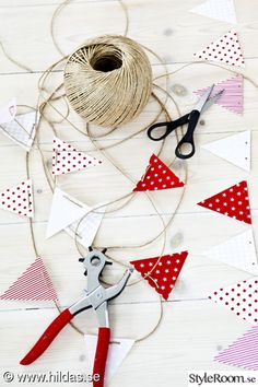 scissors, twine and spools of thread on a white wooden table with red and white bunting