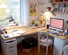 a desk with a computer on top of it in front of a window and a chair