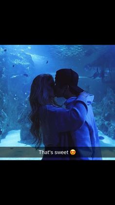 a man and woman kissing in front of an aquarium