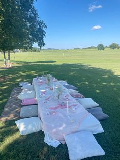 a long table set up in the middle of a field with pink and white linens on it