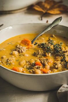 a bowl of soup with meat and carrots in it on top of a table