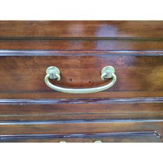 an old wooden dresser with brass handles and knobs on the front, showing it's wood grained finish