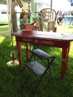 an old wooden table is sitting in the grass with other antiques on display behind it