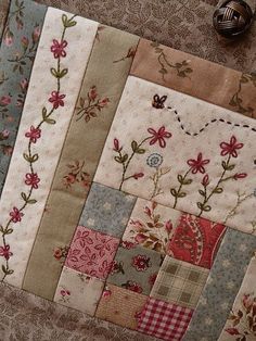 a close up of a patchwork quilt with flowers and vines on the back side