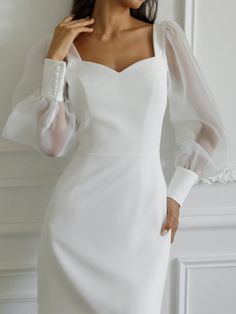 a woman wearing a white dress with long sleeves and an off the shoulder neckline