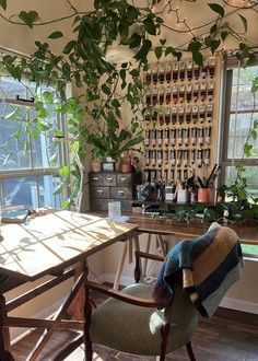 a chair sitting in front of a window next to a table with plants on it