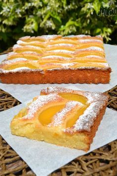 two pieces of cake sitting on top of paper next to each other in front of some bushes