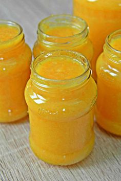 four jars filled with yellow liquid sitting on top of a table