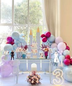 a table topped with balloons and cake next to a window