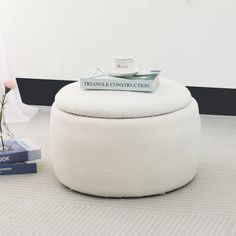 a white ottoman sitting on top of a carpeted floor next to a vase with flowers